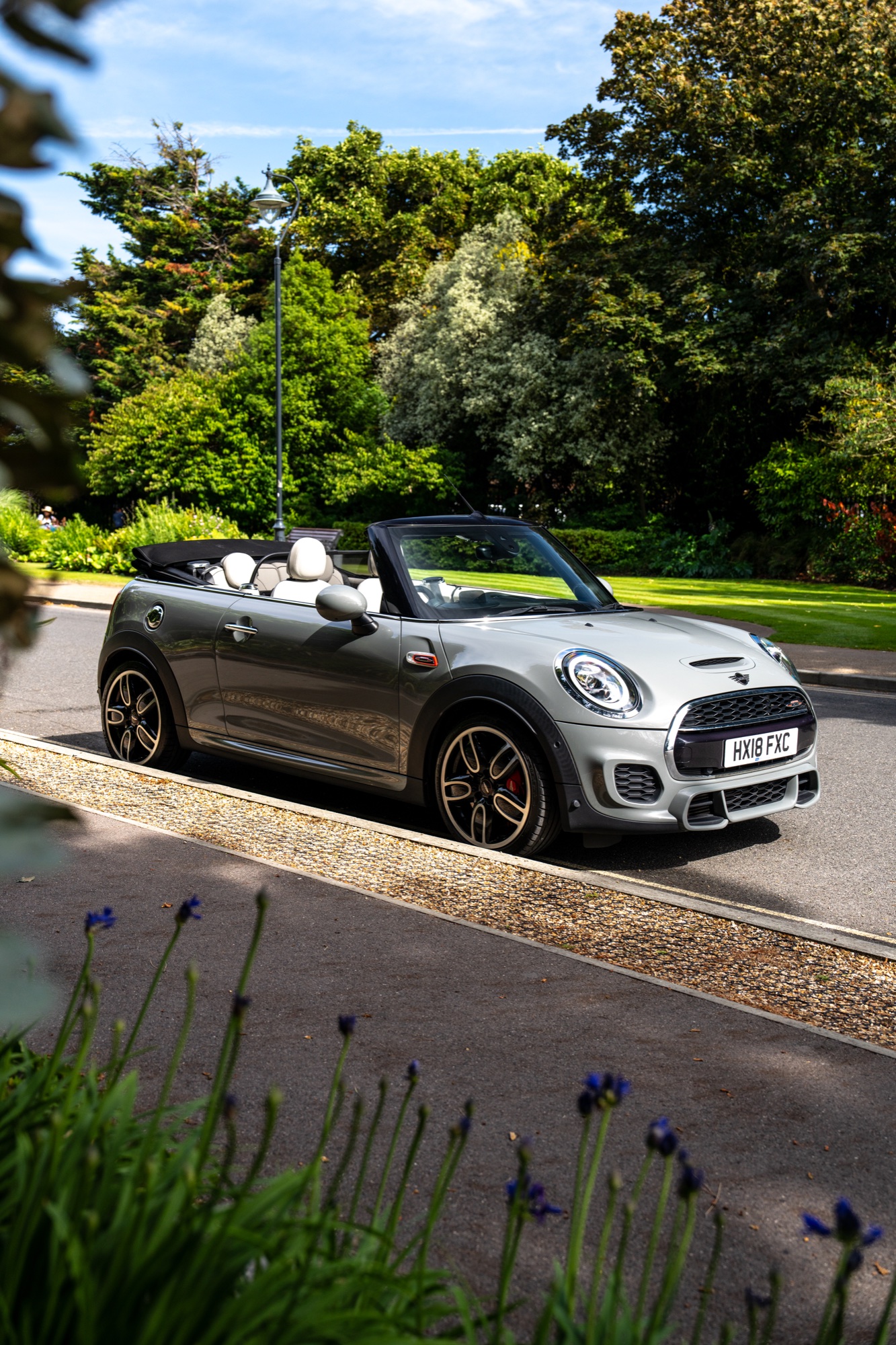 Silver Mini Cooper convertible photographed beside a green park